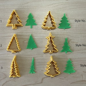 May include: Six different styles of Christmas tree cookie cutters, each shown in both a yellow and green plastic. The cutters are arranged in two rows of three, with the yellow cutters on top and the green cutters on the bottom. The cutters are labeled with numbers 1 through 6.