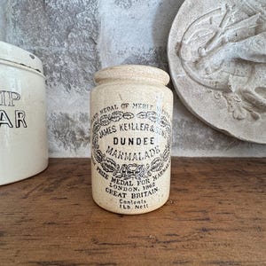 May include: A vintage Dundee Marmalade jar. The off-white ceramic jar features a black and white label with text including "James Keiller & Sons" and "Dundee Marmalade." The jar is labeled "Contents 1 lb. Net."