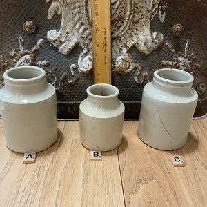 May include: Three white ceramic jars of varying sizes, labeled A, B, and C. The jars are sitting on a wooden surface.