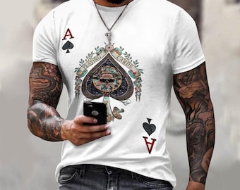 May include: White t-shirt featuring a graphic of the Ace of Spades playing card. The Ace of Spades design includes a skull and crossbones with the words "Playing Cards" surrounding it.