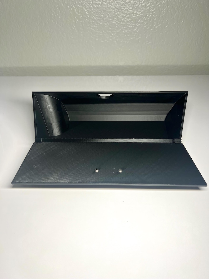 May include: A black, open-top storage box with a hinged lid. The box is made of a textured material and has a rectangular shape. Two small silver-colored rivets are visible on the lid. The box is set against a white background.