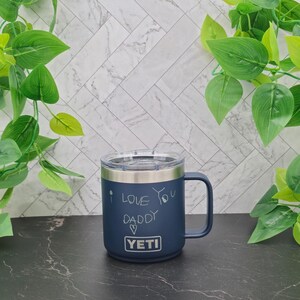 A dark blue Yeti travel mug with a stainless steel lid and handle. The mug has a white inscription that reads "I love you Daddy" with a heart symbol.