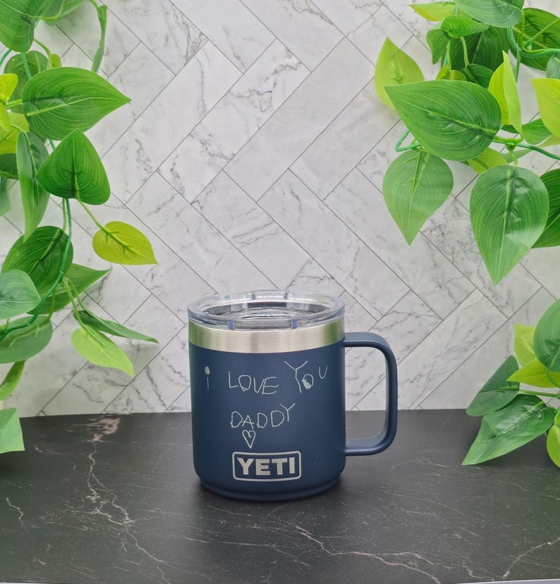 A dark blue Yeti travel mug with a stainless steel lid and handle. The mug has a white inscription that reads "I love you Daddy" with a heart symbol.