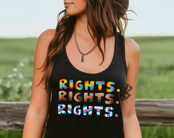 May include: A black tank top with the words "RIGHTS." repeated three times in rainbow colors. The text is layered with different colors, including brown, pink, blue, and yellow. The model is wearing a brown hat and has long brown hair.