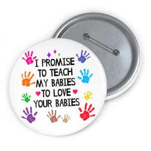 May include: White button with a colorful handprint design and the text "I promise to teach my babies to love your babies".