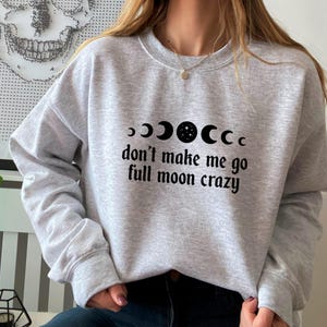 May include: Gray sweatshirt with a black graphic of a crescent moon with stars and the text "don't make me go full moon crazy".