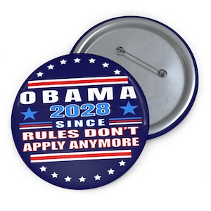 May include: A round pin-back button featuring a dark blue background with white stars along the border. The text reads OBAMA 2028 SINCE RULES DON'T APPLY ANYMORE in white and light blue, accented by red and white horizontal stripes and blue stars.