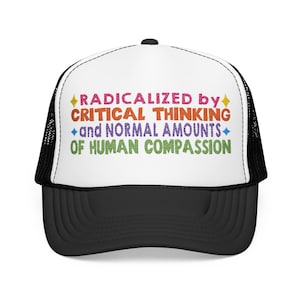 May include: A black and white trucker hat featuring the embroidered text RADICALIZED BY CRITICAL THINKING and NORMAL AMOUNTS OF HUMAN COMPASSION in multi-colored lettering with small yellow and blue star accents on the white front panel.