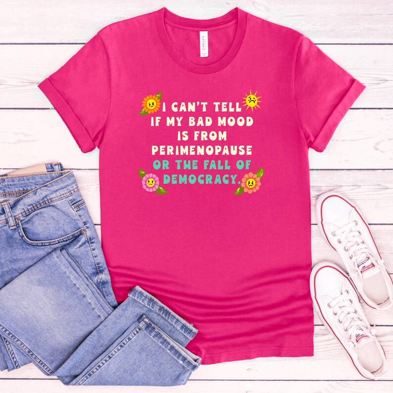 A funny and bold t-shirt featuring perimenopause humor and a political statement on the fall of democracy, designed for women who embrace activism with wit.