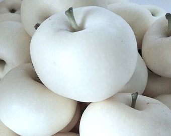 Peut inclure: Gros plan sur une pile de poires blanches. Les poires ont une forme lisse et arrondie avec une petite tige verte. La peau est d'un blanc crémeux. Les poires sont empilées, remplissant le cadre.