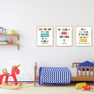 Pode incluir: Tr&ecirc;s impress&otilde;es emolduradas coloridas com texto em espanhol em uma parede branca em um quarto de crian&ccedil;a. As impress&otilde;es apresentam cita&ccedil;&otilde;es religiosas em espanhol. O quarto tem um cavalo de balan&ccedil;o de madeira, uma cama de crian&ccedil;a de madeira com roupa de cama azul e branca, e uma prateleira de madeira com brinquedos.