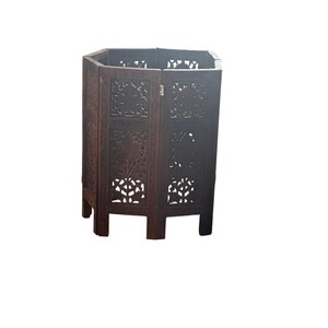 May include: A dark brown wooden hexagonal room divider with intricate carved designs. The divider has six panels and stands on six legs.