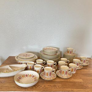 May include: A set of vintage ceramic dinnerware in a brown, orange, and white pattern. The set includes plates, bowls, cups, and saucers.