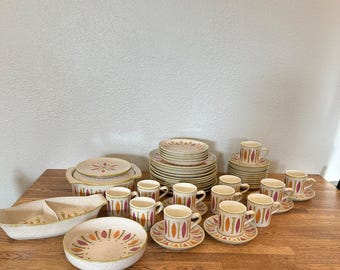 May include: A set of vintage ceramic dinnerware in a brown, orange, and white pattern. The set includes plates, bowls, cups, and saucers.