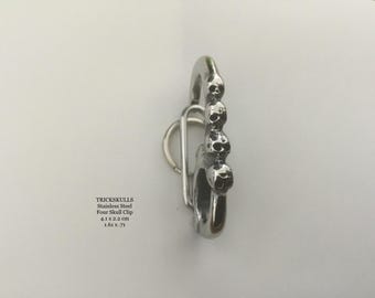 Könnte beinhalten: Ein Edelstahl-Clip mit vier Totenkopf-Designs. Der Clip ist 4,1 cm breit und 2,2 cm hoch. Der Text "TRICKSKULLS" ist sichtbar, zusammen mit dem Produktnamen und den Abmessungen.