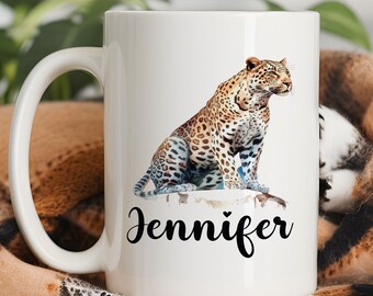 May include: White ceramic mug with a watercolor illustration of a leopard sitting on a white background. The mug has a black handle and the name "Jennifer" is printed in black below the image.