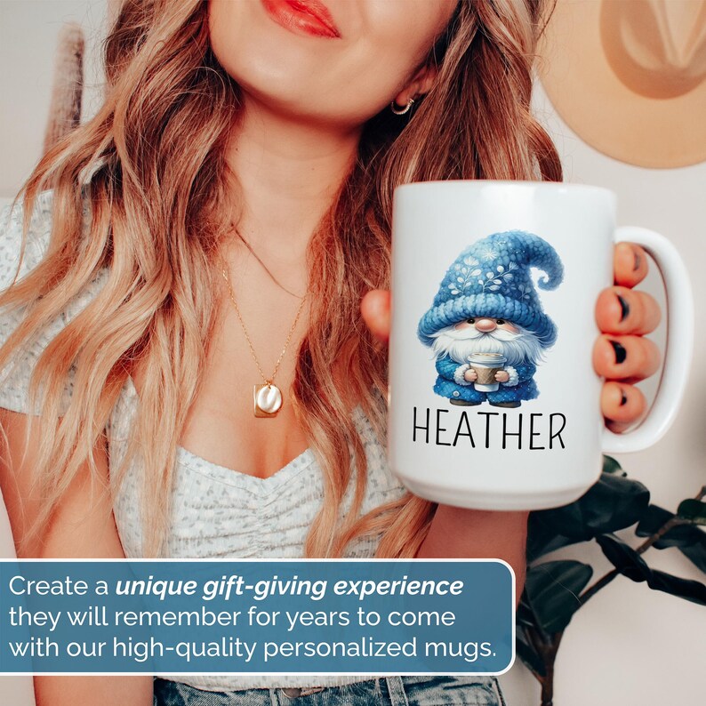 May include: A white ceramic mug with a blue gnome illustration and the name 'HEATHER' printed in black text. The gnome is wearing a blue hat with white snowflakes and holding a cup of coffee.