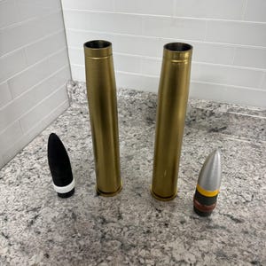 May include: Two gold-coloured metal cylinders and two bullet-shaped objects. One bullet is black with a white band, and the other is silver with a yellow band.