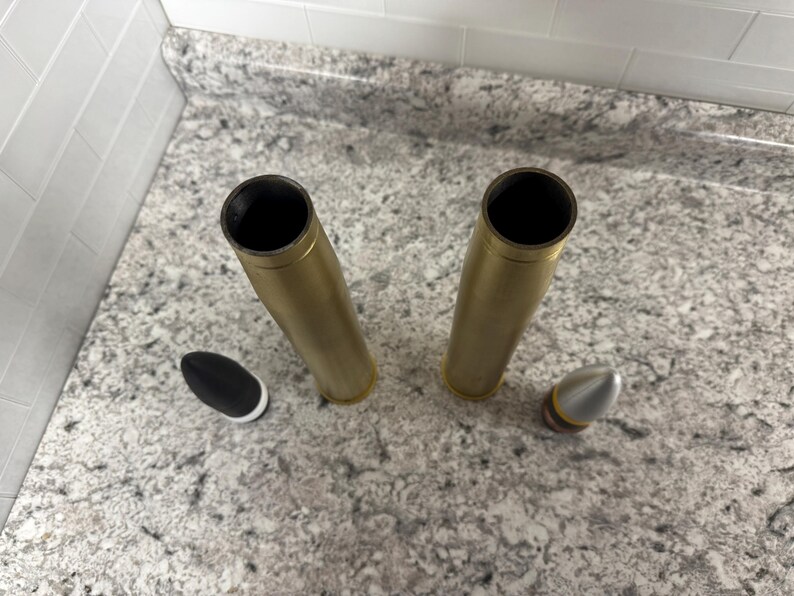 May include: Two gold-coloured metal casings with black and silver bullet tips.