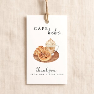 May include: White gift tag with the text "CAFE bébé" and "thank you FROM OUR LITTLE BEAN". The tag features a watercolor illustration of a croissant, cinnamon roll, and a coffee drink with whipped cream.