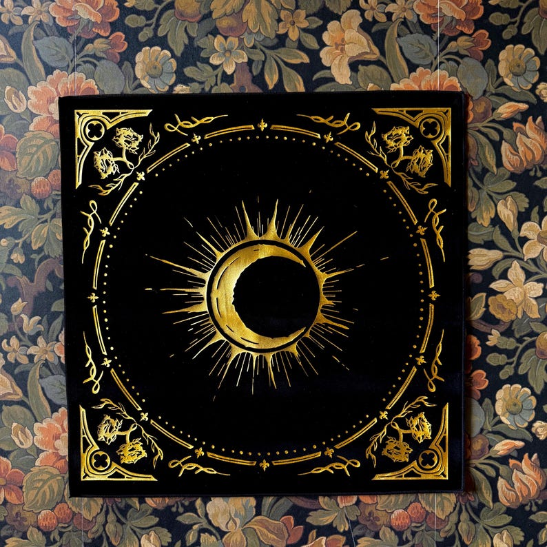 May include: A black velvet square with a gold sun and crescent moon design. The design is surrounded by a decorative border.