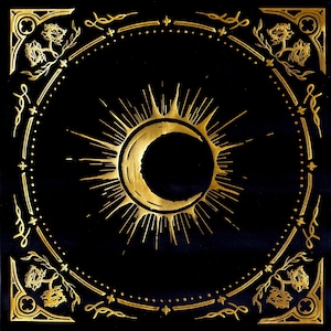 May include: A black square background with a gold sun and crescent moon design. The design is surrounded by a gold ornate border with floral motifs.