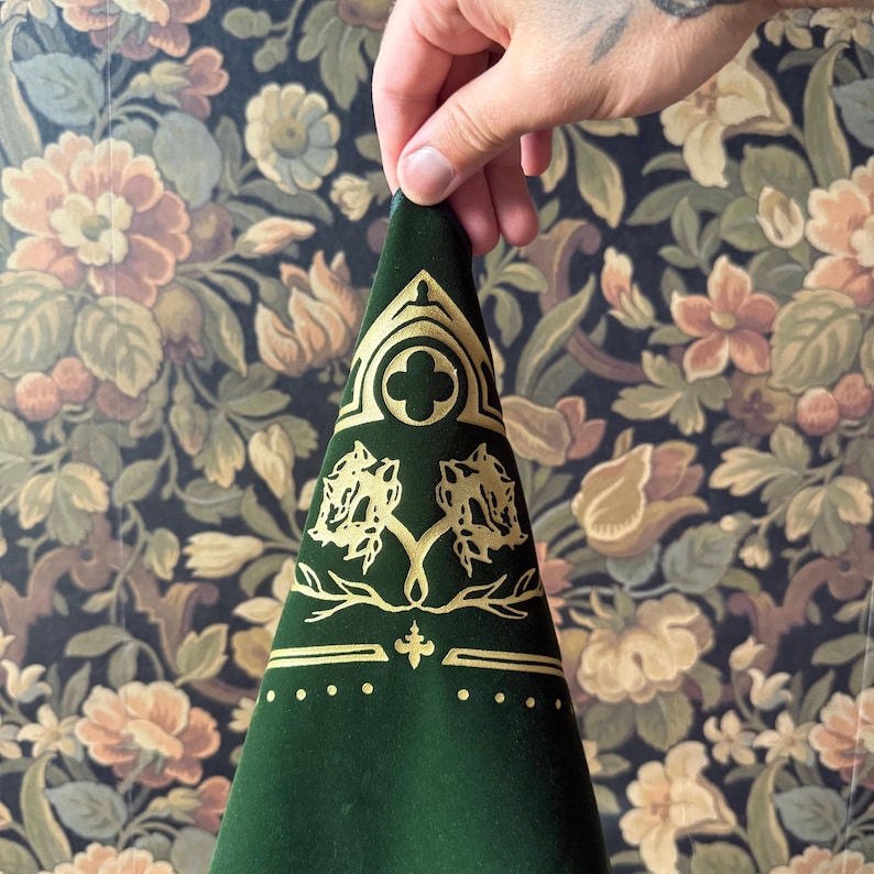 May include: A green velvet fabric with gold embroidery. The design features a quatrefoil, two stylized trees, and a fleur-de-lis.