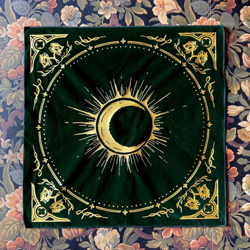 May include: A green velvet bandana with a gold crescent moon and sun design. The bandana has a gold border with a repeating floral pattern.