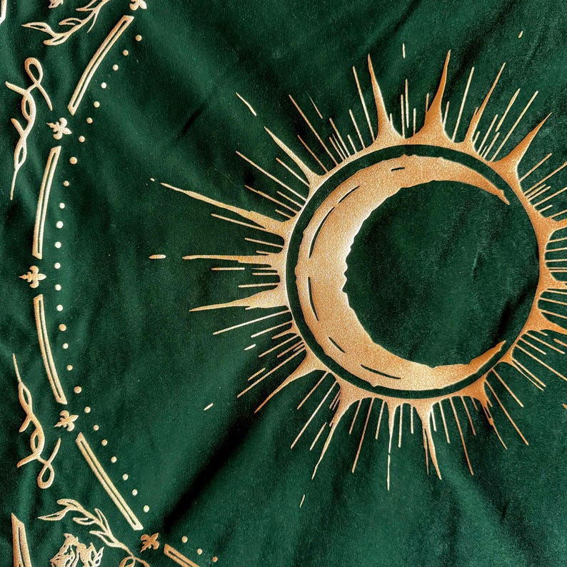 May include: A green tapestry with a gold crescent moon and sun design. The sun has a radiating pattern of gold lines.