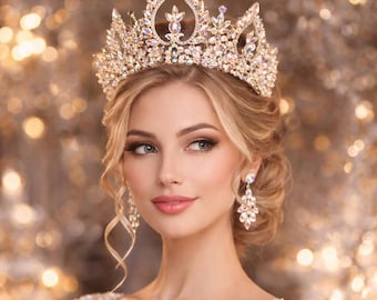 May include: A woman wearing a gold-coloured crown and matching earrings. The crown is decorated with clear and iridescent crystals. The woman has blonde hair and is wearing a white dress with embellished details. The background is a soft, blurred bokeh of golden lights.