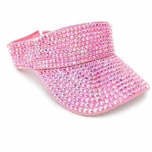 Puede incluir: Visera rosa cubierta de pedrer&iacute;a iridiscente. La visera tiene una visera curvada y una banda para la cabeza. Los brillantes est&aacute;n muy juntos, creando un efecto brillante. Accesorio de moda.