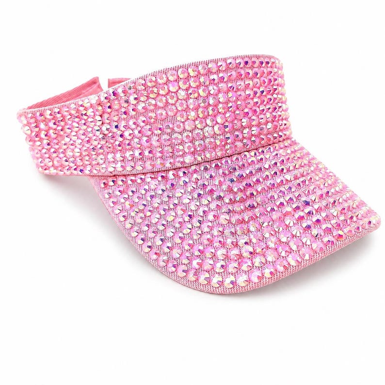 Puede incluir: Visera rosa cubierta de pedrer&iacute;a iridiscente. La visera tiene una visera curvada y una banda para la cabeza. Los brillantes est&aacute;n muy juntos, creando un efecto brillante. Accesorio de moda.