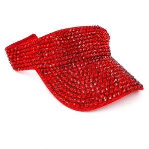 Puede incluir: Una vibrante visera roja, completamente incrustada con brillantes pedrer&iacute;a. La visera presenta una visera curvada y una banda el&aacute;stica c&oacute;moda. Este accesorio a&ntilde;ade un toque de glamour y es perfecto para los d&iacute;as soleados.