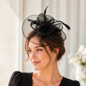 以下が含まれることがあります： 円形のベースと、重ねられた生地と羽のアクセントが特徴の黒いファシネーター。 ヘッドピースは、透明で軽量な素材で作られています。 画像の女性は黒いドレスを着ています。 スタイリッシュなアクセサリーです。