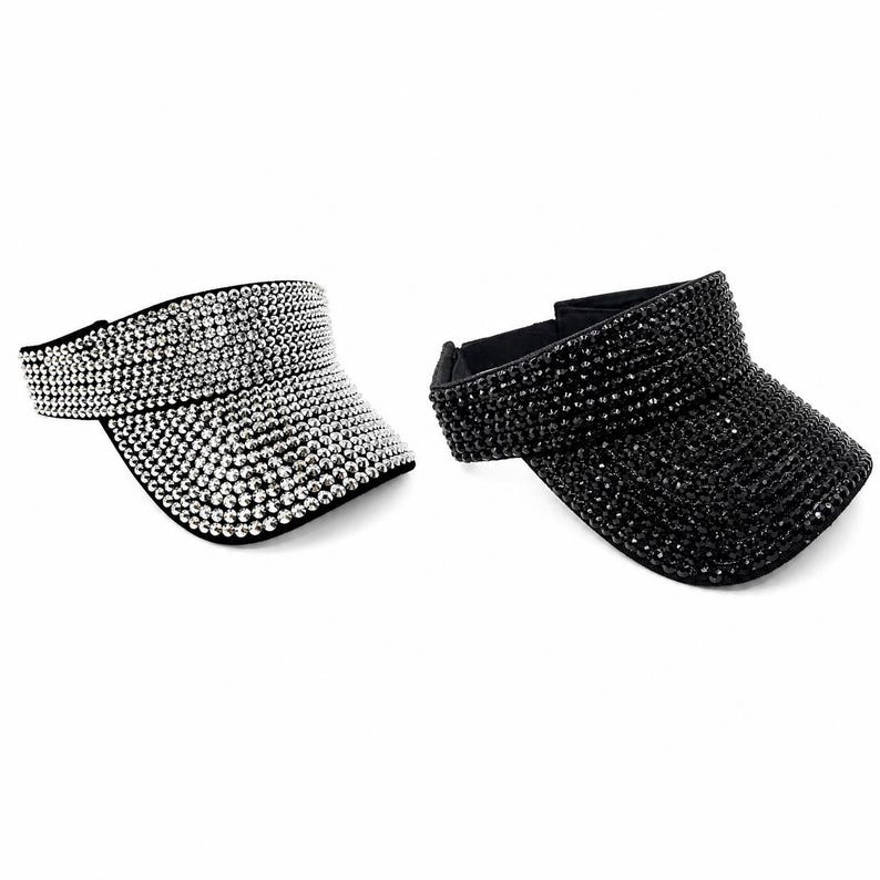 Puede incluir: Se muestran dos viseras, una plateada y otra negra. La visera plateada est&aacute; cubierta de brillantes pedrer&iacute;a, mientras que la visera negra tiene un dise&ntilde;o similar. Ambas viseras tienen una visera curva y una banda para la cabeza.