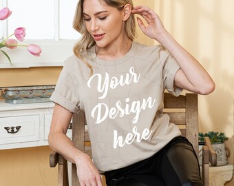 May include: A woman wearing a beige t-shirt with the text "Your Design here" printed on the front. She is sitting on a wooden chair.