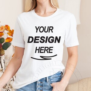 Pode incluir: Camiseta branca com o texto "YOUR DESIGN HERE" estampado na frente.