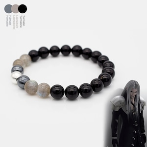 Könnte beinhalten: Ein Perlenarmband mit schwarzen Turmalin-, Labradorit- und Hämatitsteinen. Das Armband hat eine Mischung aus schwarzen, grauen und irisierenden Perlen. Das Armband befindet sich auf weißem Hintergrund.