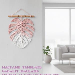 May include: A macrame wall hanging in the shape of a leaf, featuring a gradient of pink to white. The leaf is suspended from a natural wooden dowel with a pink string. Text at the bottom reads "MACRAME TEMPLATE GABARIT MACRAME FORMAT AI DXF LBRN SVG PDF".