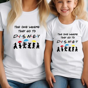May include: White t-shirts for adults and children with the text "The one where they go to Disney" and a graphic of Mickey Mouse and friends walking with umbrellas.