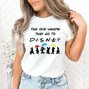 May include: White t-shirt with the text "The one where they go to DISNEY" in black with a heart around each letter.  Below the text are six black silhouettes of Mickey Mouse characters holding colorful umbrellas.