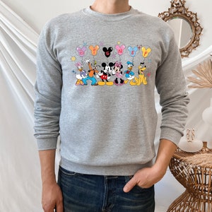 May include: A gray sweatshirt with a print of Mickey Mouse and his friends holding balloons that spell out "DISNEY".