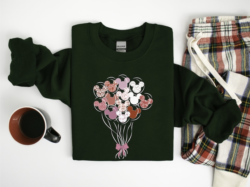 May include: A dark green sweatshirt with a white graphic of a bouquet of pink, red, and white Mickey Mouse head balloons tied with a pink bow.