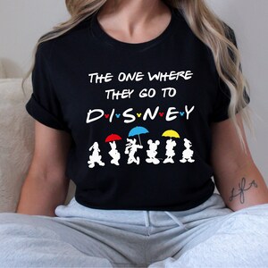 May include: Black t-shirt with the text "The One Where They Go To Disney" and a line of Mickey Mouse characters holding umbrellas.