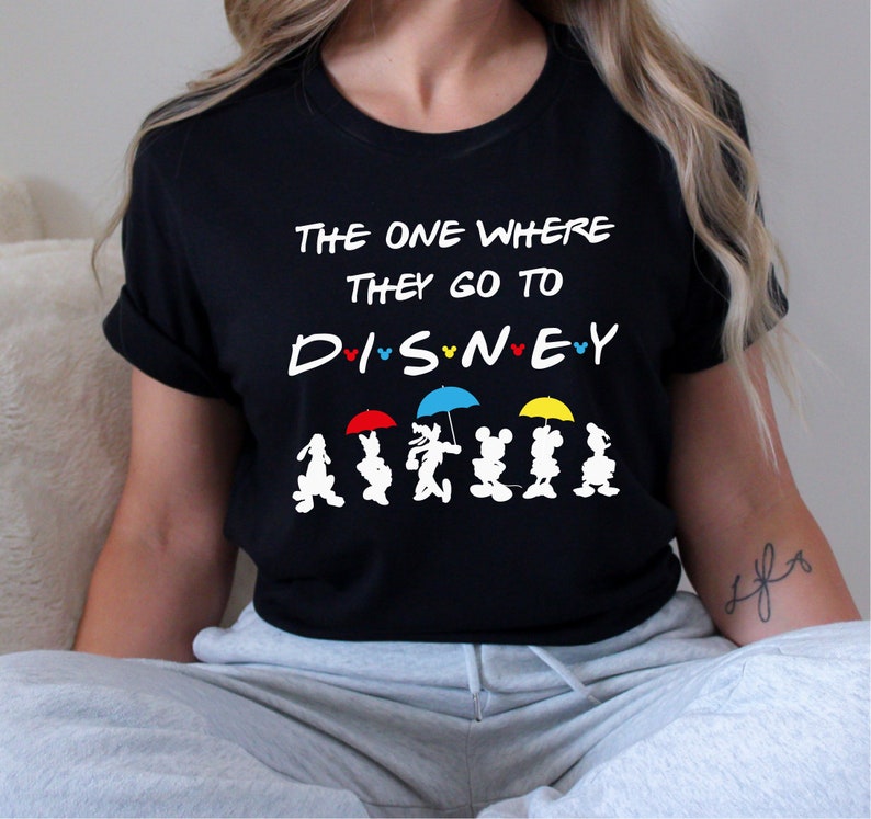 May include: Black t-shirt with the text "The One Where They Go To Disney" and a line of Mickey Mouse characters holding umbrellas.