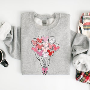 May include: A gray sweatshirt with a design of pink and red Mickey Mouse heads shaped like balloons. The balloons are tied together with a pink ribbon.