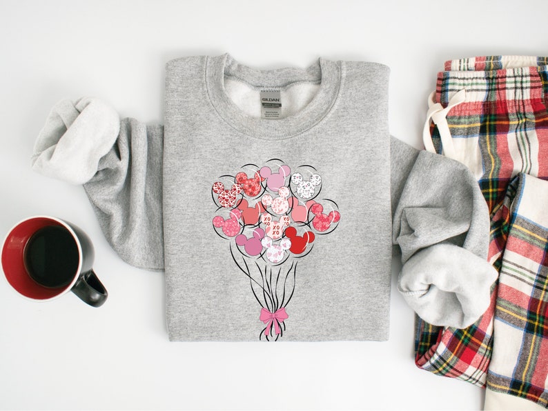May include: A gray sweatshirt with a design of pink and red Mickey Mouse heads shaped like balloons. The balloons are tied together with a pink ribbon.
