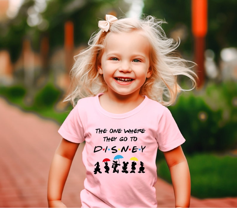 May include: A pink t-shirt with the text "The one where they go to DISNEY" with hearts and cartoon characters holding umbrellas.