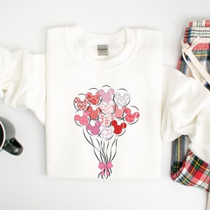 May include: White sweatshirt with a pink and red Mickey Mouse head balloon design. The balloons are tied together with a pink ribbon.