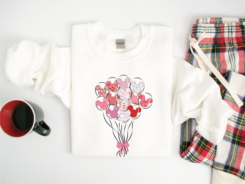 May include: White sweatshirt with a pink and red Mickey Mouse head balloon design. The balloons are tied together with a pink ribbon.
